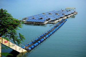 การหันมาใช้พลังงานหมุนเวียนเป็นเรื่องที่ทุกประเทศให้ความสนใจกันอย่างล้นหลาม เพราะเป็นพลังงานที่สะอาด และเป็นมิตรต่อสิ่งแวดล้อม แต่พลังงานหมุนเวียนก็ยังมีข้อจำกัดที่ว่า ‘ยังไม่เสถียร’ เพราะพลังงานหมุนเวียนแต่ละชนิดจะมีข้อจำกัดที่แตกต่างกัน การนำพลังงานหมุนเวียนหลากหลายรูปแบบเข้ามาผสานกันเพื่อสร้างเสถียรภาพ (Firm) ด้วยระบบ Integrated Renewable Firm Power System จึงเป็นหนึ่งทางเลือกที่ การไฟฟ้าฝ่ายผลิตแห่งประเทศไทย (กฟผ.) จะนำมาใช้ในการผลิตไฟฟ้าเพื่อแก้ไขข้อจำกัด ให้พลังงานหมุนเวียนสามารถจ่ายไฟฟ้าได้เต็มศักยภาพ และเสถียรมากที่สุด โครงการ Hydro-Floating Solar Hybrid ที่ใหญ่ที่สุดในอาเซียน (ASEAN) รูปแบบที่ กฟผ. จะดำเนินการเป็น “ระบบ Hydro-Floating Solar Hybrid” หรือระบบผลิตไฟฟ้าผสมผสานระหว่าง ‘พลังน้ำจากเขื่อน’ และ ‘พลังงานแสงอาทิตย์จากโซลาร์เซลล์ลอยน้ำบนเขื่อน’ ซึ่งจะเป็นโครงการไฮบริดที่มีขนาดใหญ่ที่สุดในอาเซียน (ASEAN) ที่มีจุดเด่นของโครงการคือ 1. ราคาต่ำ โดยองค์ประกอบที่ทำให้ราคาต่ำ ได้แก่ - เป็นโครงการขนาดใหญ่ที่มีกำลังผลิตมากกว่า 30 เมกะวัตต์ขึ้นไป (Economy of Scale) - ใช้โครงสร้างของระบบไฟฟ้าเดิมที่ กฟผ. มีรองรับอยู่เช่น ระบบเชื่อมต่อไฟฟ้า หม้อแปลงไฟฟ้า โดยใช้ให้เกิดประสิทธิภาพสูงสุด และบริหารจัดการพื้นที่ที่มีอยู่ให้เกิดประโยชน์สูงสุด (Maximized Existing Facility) 2. เสริมความมั่นคงของระบบไฟฟ้า ด้วยระบบ Integrated Renewable Firm Power System โดยโครงการจะเริ่มที่ระบบ Hydro-Floating Solar Hybrid และในอนาคตสามารถพัฒนาร่วมกับระบบกักเก็บพลังงาน (Energy Storage System) เพื่อให้ระบบไฟฟ้ามีความมั่นคงมากขึ้น 3. ไม่กระทบต่อชุมชน และสิ่งแวดล้อม - จะใช้พื้นที่ผิวน้ำบนเขื่อน กฟผ. ในการติดตั้งโซลาร์เซลล์ลอยน้ำ ทำให้ไม่กระทบกับพื้นที่การเกษตร และเส้นทางการเดินเรือของชุมชน และผู้ที่ใช้ชีวิตประจำวันในบริเวณพื้นที่เขื่อน - ใช้เทคโนโลยีในการสำรวจ และตรวจสอบสภาพสิ่งแวดล้อม เช่น ระบบสารสนเทศ (GIS) และหุ่นยนต์ถ่ายภาพใต้น้ำ - วัสดุที่ใช้ในการติดตั้งโซลาร์เซลล์ลอยน้ำเป็นแบบเดียวกับท่อประปา จึงเป็นมิตรกับสิ่งแวดล้อม เดินหน้าโครงการนำร่อง 2 เขื่อน ปัจจุบัน กฟผ. อยู่ในช่วงสำรวจการติดตั้งโครงการโซลาร์เซลล์ลอยน้ำใน 9 เขื่อน ทั่วประเทศไทย พบว่า มีศักยภาพติดตั้งโซลาร์เซลล์ได้มากถึง 2,725 เมกะวัตต์ จึงมีแผนจะเริ่มโครงการนำร่องก่อน จำนวน 2 โครงการ ได้แก่ 1. เขื่อนสิรินธร จ.อุบลราชธานี กำลังผลิต 45 เมกะวัตต์ 2. เขื่อนอุบลรัตน์ จ.ขอนแก่น กำลังผลิต 24 เมกะวัตต์ ช่วยบริหารจัดการน้ำให้เกิดประโยชน์สูงสุด หลักการทำงานของระบบดังกล่าว ไม่เพียงช่วยเสริมความมั่นคงของระบบไฟฟ้า แต่ยังช่วยในเรื่องของการบริหารจัดการน้ำให้เกิดประสิทธิภาพสูงสุดได้ - ในกรณีที่ปริมาณน้ำมีมากพอ เขื่อนจะผลิตไฟฟ้ารองรับความพร้อมจ่ายของระบบสูงสุดได้' - ในกรณีที่ปริมาณน้ำมีจำกัด โซลาร์เซลล์จะช่วยให้มีการบริหารจัดการน้ำมีความยืดหยุ่น เช่น ผลิตไฟฟ้าจากพลังงานแสงอาทิตย์ในช่วงกลางวัน และการนำพลังน้ำมาเสริมในช่วงความต้องการไฟฟ้าสูง (กำลังการผลิตมากเพื่อเสริมช่วง Peak) ในเวลากลางคืน หรือการเดินเครื่องโรงไฟฟ้าพลังน้ำต่อเนื่อง แต่กำลังการผลิตน้อยเพื่อเสริมความต้องการของระบบไฟฟ้า แนวคิดการนำพลังงานหมุนเวียนมาใช้งานผสมผสานเพื่อเสริมความมั่นคงของระบบไฟฟ้า เป็นความพยายามของ กฟผ. ในการพัฒนาพลังงานสะอาดควบคู่ไปกับภารกิจการสร้างเสถียรภาพทางไฟฟ้าให้คนไทยตามวิสัยทัศน์ กฟผ. ที่ว่า “นวัตกรรมพลังงานไฟฟ้าเพื่อชีวิตที่ดีกว่า” ข้อมูล: https://www.egat.co.th